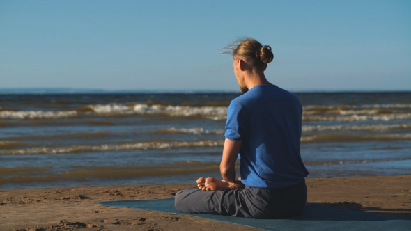 Man in Lotus Pose Meditating at the Beach