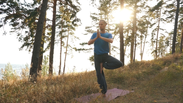 Young Man Doing Yoga in the Woods at Sunset