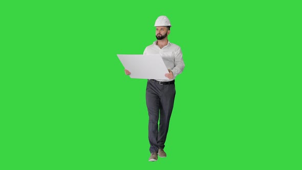 Confident Young Architect in White Shirt and Hardhat Looking at Blueprint While Walking on a Green