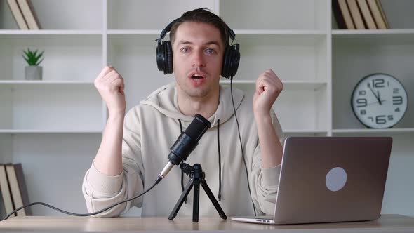 Handsome Young Man Blogger Recording Audio Talking in Microphone and Looking at Camera in Office