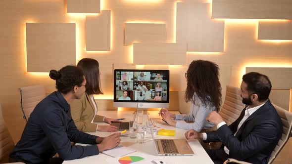 Confident Business People Sitting at the Desk with a Computer Chatting with Colleague