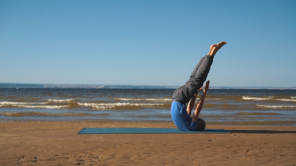 Young Man Doing Thoracic Stretching on a Rock at Sunset Light