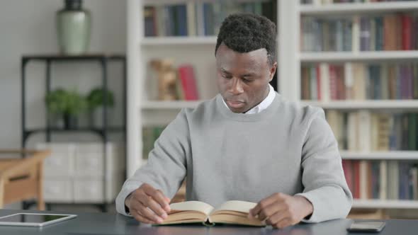 African Man Reading Book While Sitting in Library