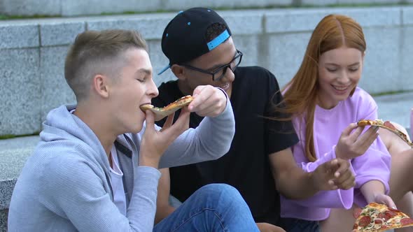 Happy Males and Female Friends Greedily Enjoying Tasty Pizza Outdoors, Snack