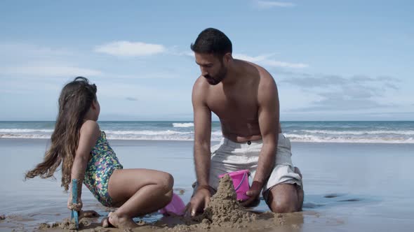 Sweet Little Girl and Her Dad Building Sand Castle