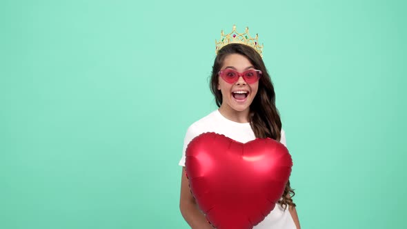 Portrait of Happy Teen Girl in Sunglasses and Crown Hold Heart Party Balloon Dream