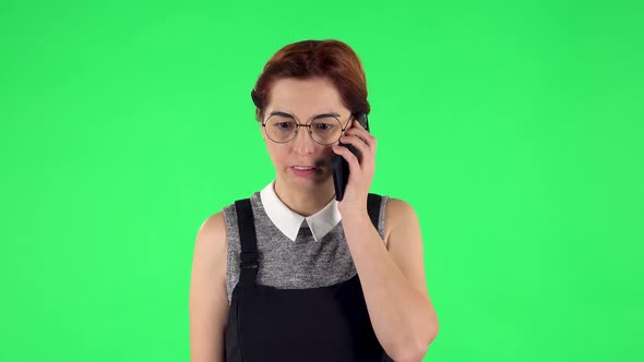 Portrait of Funny Girl in Round Glasses Is Angrily Talking for Mobile Phone. Green Screen