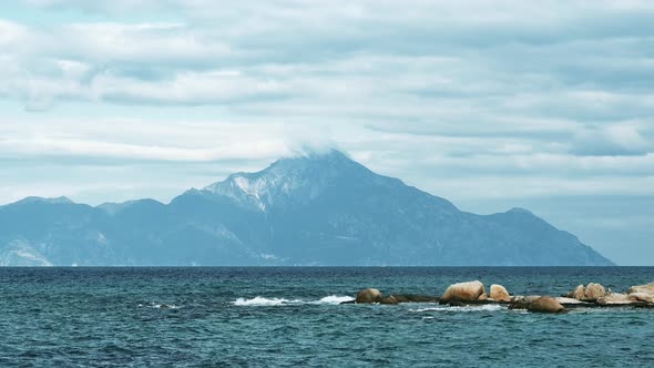 Mountain reaching clouds in the distance with Aegean sea on the foreground in Greece