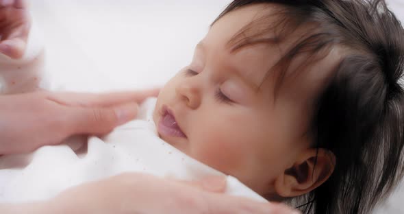 Mom Strokes Her Little Daughter Lying on the Bed Takes Her in Her Arms