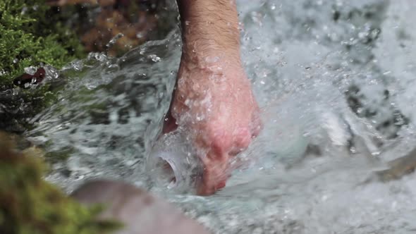 Close up, man's hand filling up reusable water bottle with clean river water