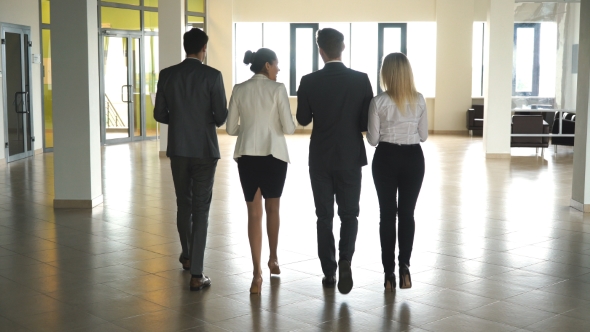 Four Business People Talking and Walking in Office Lobby