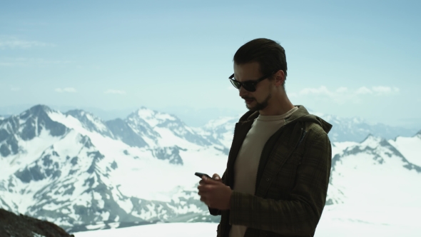 Young Bearded Man Receives Phone Call at Snowy Mountains with Scenic View
