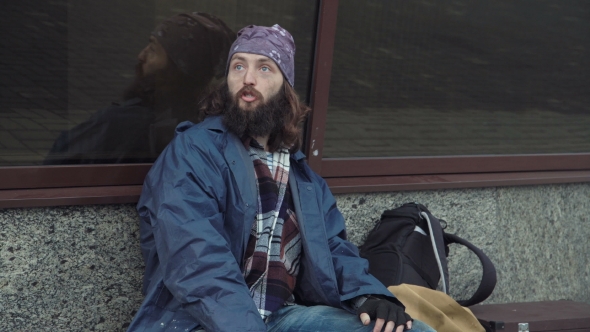 A Drunken Homeless Man Is Sitting on the Street.