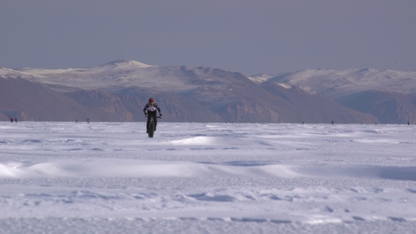 a Man Riding a Bicycle Across a Frozen Lake