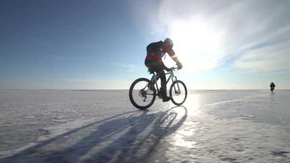 a Man Riding a Bicycle Across a Frozen Lake