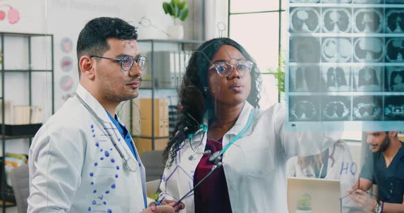 Doctors Discussing X-ray Scan Attached to the Glass wall in Medical Office