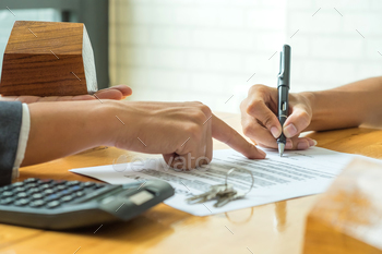 a broker,model house in broker hand and calculator with a house key on the table.