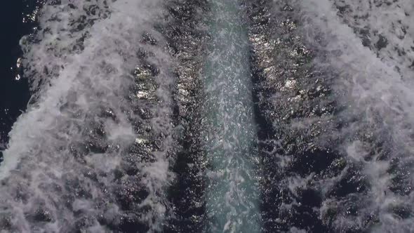 Aerial view of small speed boat with trailing wake on sea.