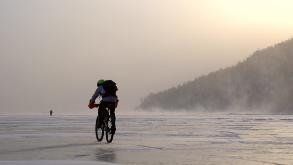 a Man Riding a Bicycle Across a Frozen Lake