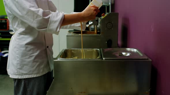 Worker pouring white melting chocolate in container