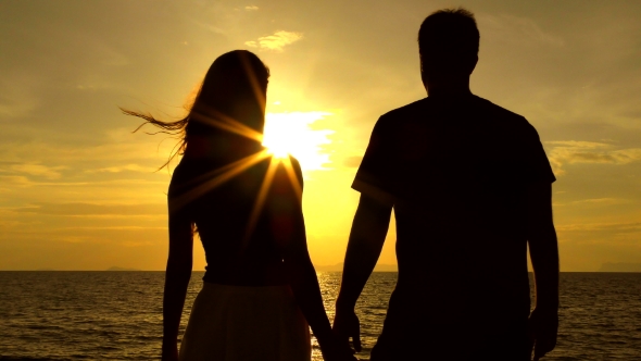 Romantic Couple on the Beach at Colorful Sunset on Background