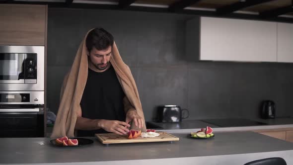 Portrait of a Man Serving Grapefruit Slices on Plate at Kitchen in the Morning