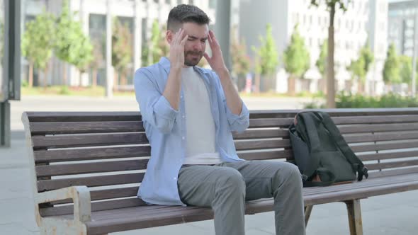 Young Man with Headache Sitting on Bench