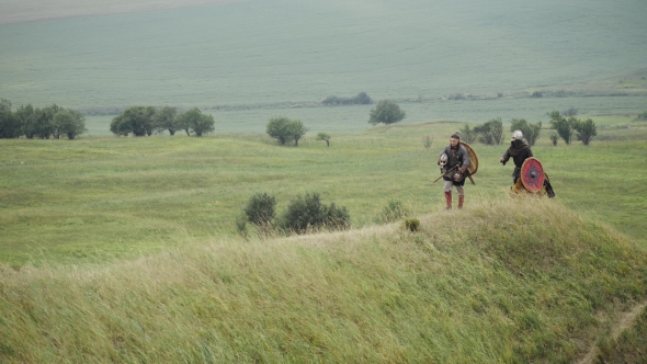 Group of Viking with Shields Walking Forward on the Meadow