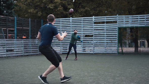 Two Men Practising American Football on Field