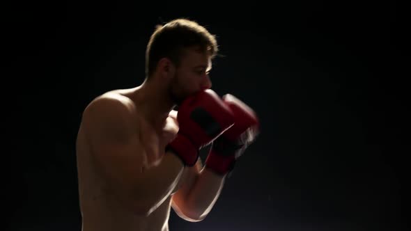 Young Boxer Is Training on Dark Background.