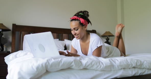 Young Woman Using Laptop Computer Typing Beautiful Girl Lying On Bed In Bedroom Morning