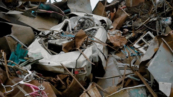 Old Crushed Car Is Lying in Heap of Metal Rubbish in a Dumping Outdoors in Gloomy Day, Waste