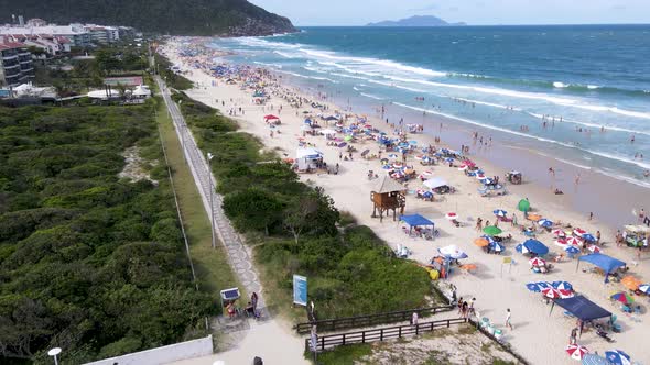 Aerial view of tropical tourist beach with hotels and summer houses facing the sea with many people