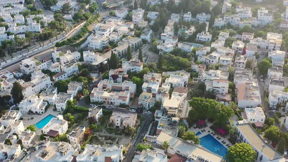Aerial street view of white villas in Bodrum Turkey as the sun sets over the homes during a sunny su