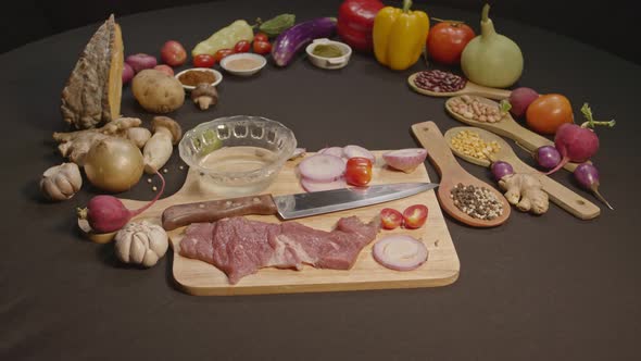 Fresh Meats, Vegetables And Spices Are Laid Out On A Black Table