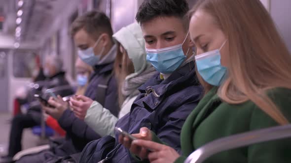 Masked Subway Passengers Using Phones in Transport