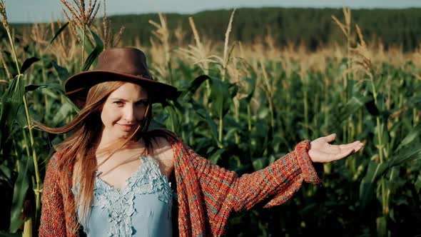 Portrait of Young Farmer Girl in Hat Shows Up with Hand Her Corn Field at Organic Farm. Girl Smiling