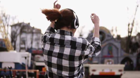 In Headphones and Sunglasses Trendy Girl is Dancing and Jumping in a Funny Way