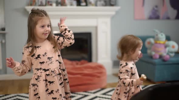 Picture of Friendly Two Small Girls in Cute Dresses Waving Hands and Playing Around While Resting at