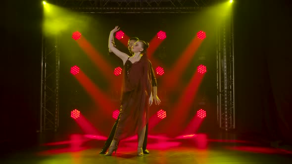 A Romantic Couple of Ballroom Dancers Are Dancing in the Studio Against the Background of Red