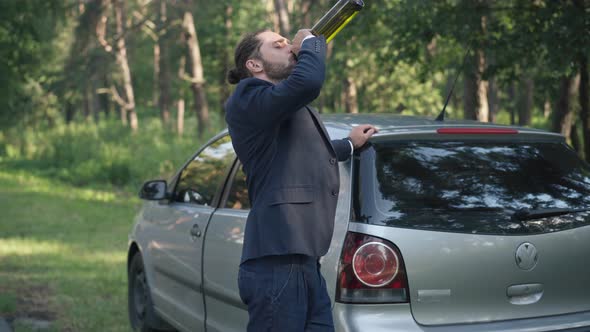 Side View Portrait of Young Drunk Caucasian Businessman in Suit Standing at Car on Suburban Road