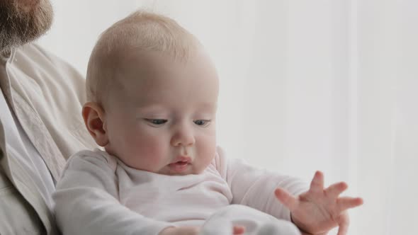 Closeup of Little Caucasian Cute Funny Infant Newborn Daughter Son with Unrecognizable Father