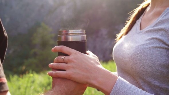 Tourists Drink Tea From a Mug of Thermos on the Background of Mountains
