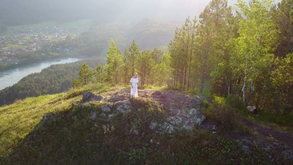 A Girl in a White Dress Is Standing on a Mountain a Beautiful View From Above