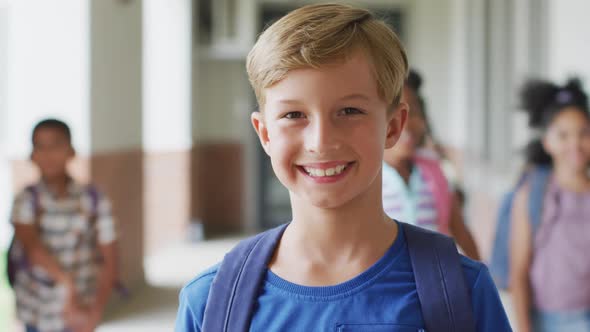 Video of happy caucasian boy standing at school corridor