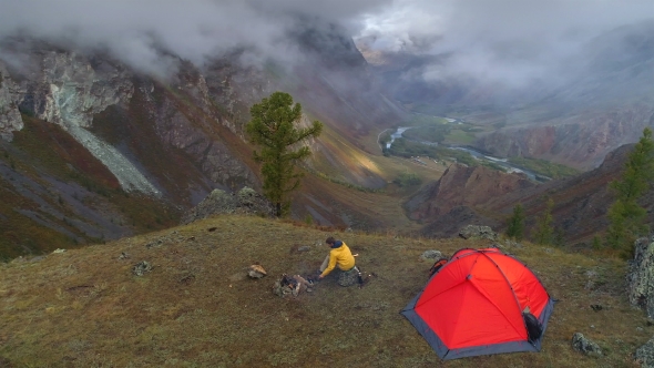 Aerial Shot of Camping and a Man Sitting and Looking Around at the View