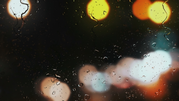 Raindrops on a Car Window with Blurred Background of Street Traffic Lights alt