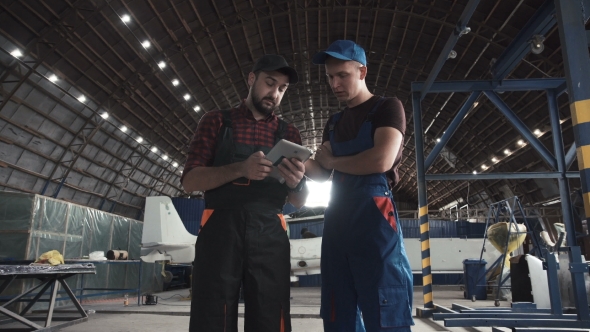 Two Men Discussing in Aircraft Hangar