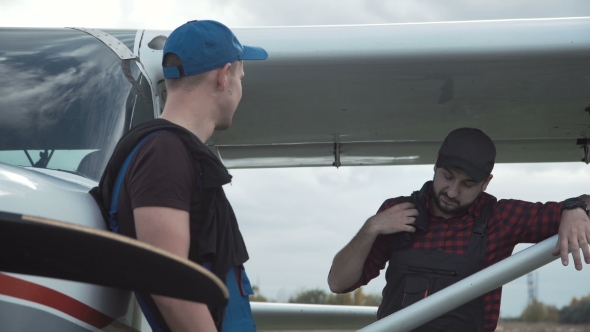 Pilot and Mechanic Chatting on an Airfield
