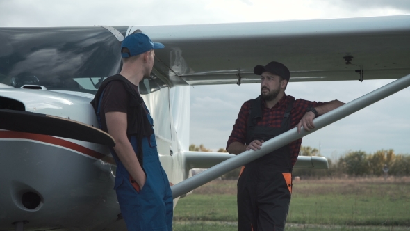 Pilot and Mechanic Chatting on an Airfield